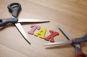 Two scissors with the word tax on the wooden background